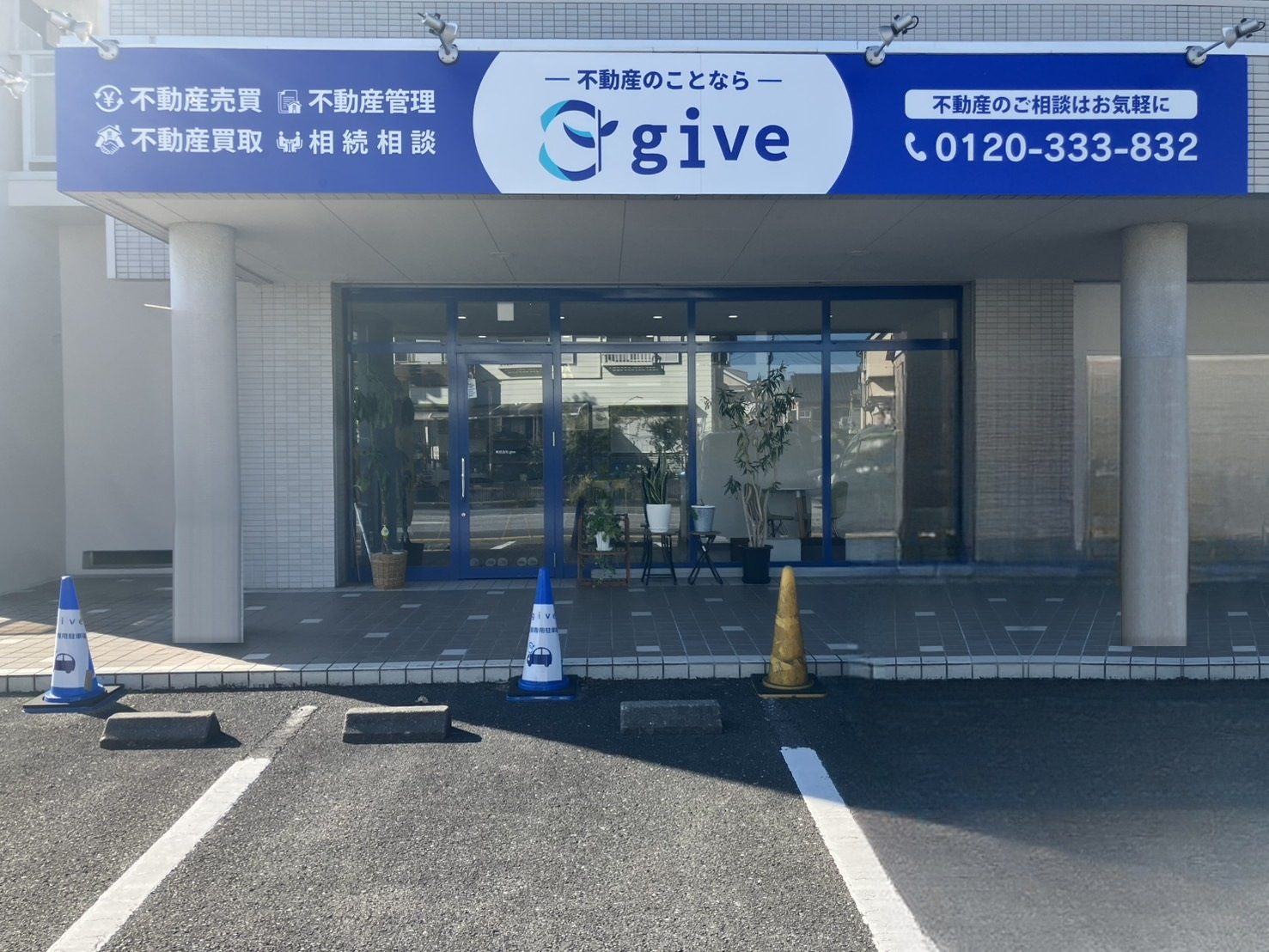 株式会社give本店の正面外観。青い看板と店舗入口