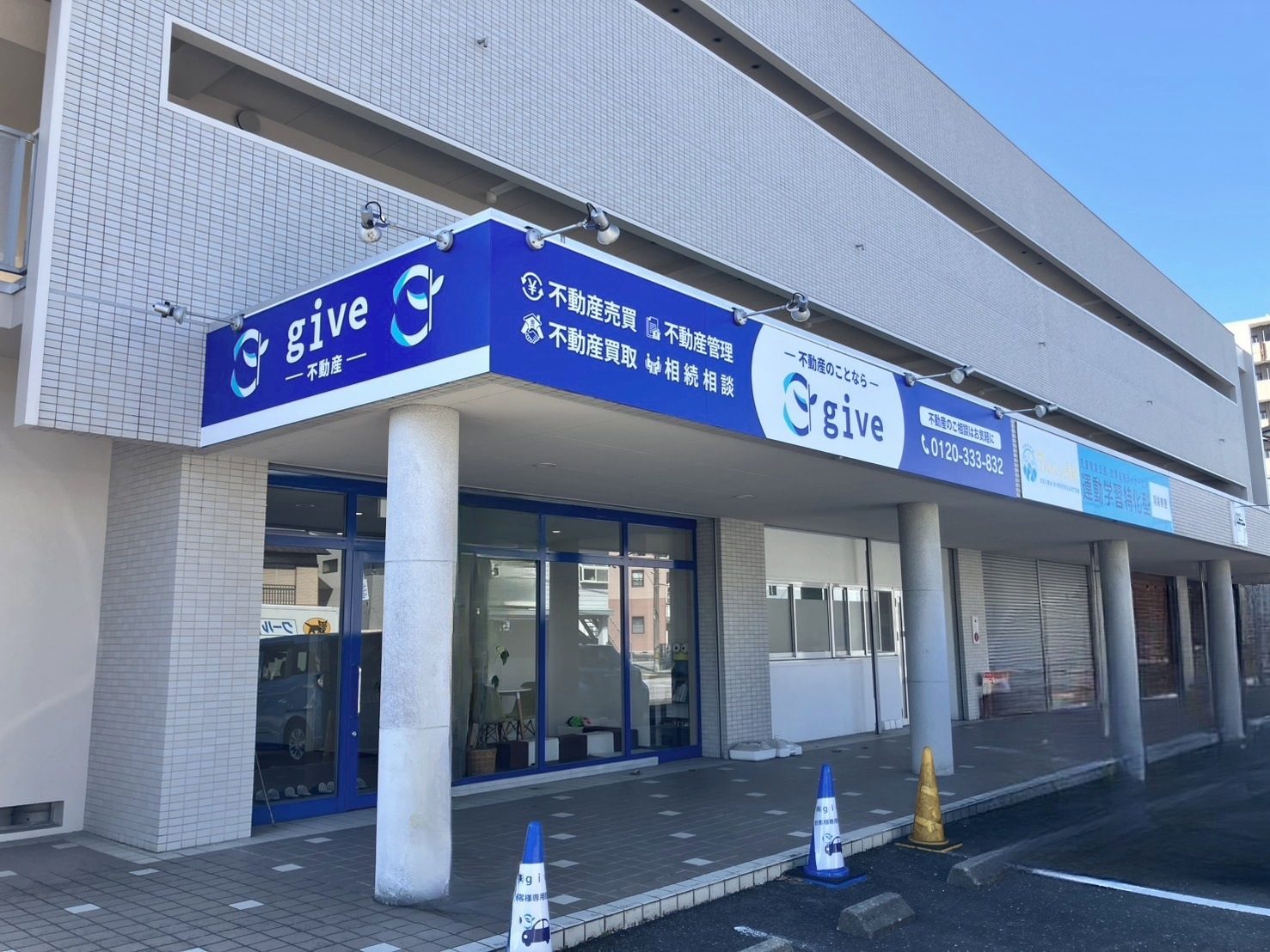 高知市朝倉横町にある株式会社give本店の外観。青いgive不動産の看板と店舗入口
